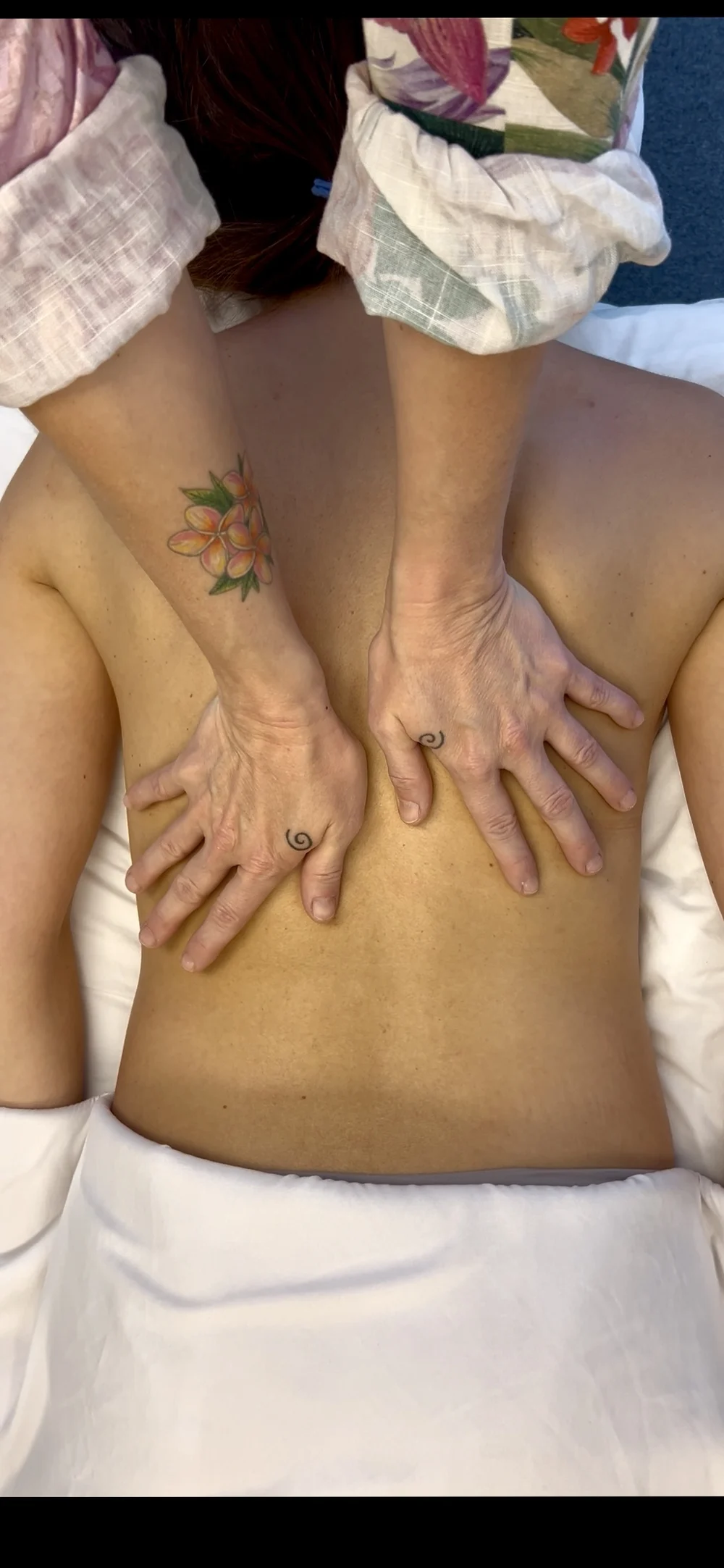 A therapist's hands resting on a client's back during a massage at The Teal Center Arlington